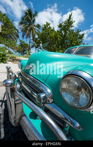 VARADERO, Kuba - 7. Juni 2011: Klassische amerikanische Auto steht geparkt vor Palmen auf der Straße neben dem Strand. Stockfoto