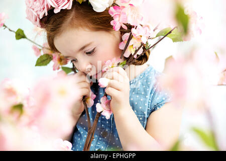 Niedliche kleine Mädchen unter frische Blumen Stockfoto