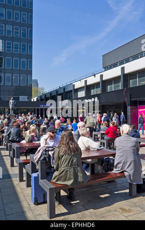 Reisende warten bei Sonnenschein im Sitzbereich außerhalb beschäftigt Euston Station, (derzeit renoviert), central London UK Stockfoto