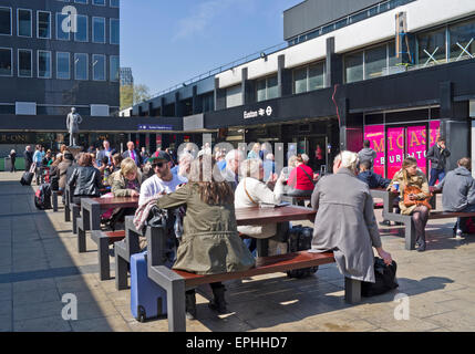 Reisende warten bei Sonnenschein im Sitzbereich außerhalb beschäftigt Euston Station, (derzeit renoviert), central London UK Stockfoto