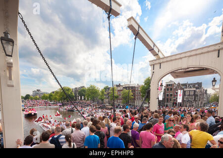 Amsterdam Gay Pride Canal Parade mit Scharen von Besuchern auf die Magere Brug oder Magere Brücke über den Fluss Amstel Stockfoto