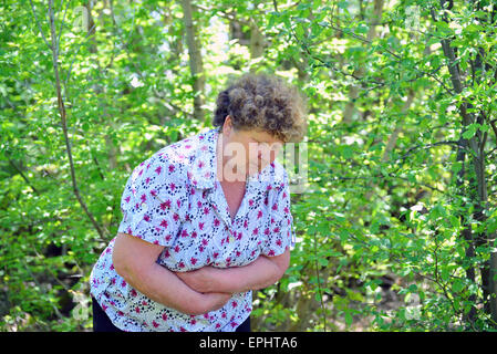 Reife Frau mit Schmerzen im Unterleib in der Natur Stockfoto