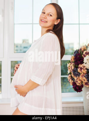 Lächelnde schwangeren Frauen am Fenster Stockfoto