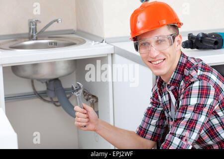 Klempner in der Nähe der Küchenspüle lächelnd Stockfoto