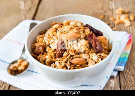 Vollkorn-Müsli zum Frühstück, mit vielen trockenen Früchten, Nüssen und Körnern hautnah, horizontal, auf Holztisch mit Löffel Stockfoto