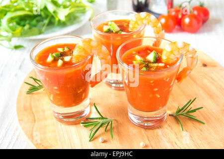 lecker lecker kalte Tomaten Suppe Gazpacho mit Avocado und Garnelen in Teil Brille auf Holzbrett, Closeup, horizontal Stockfoto