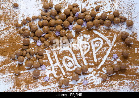 Schokokugeln auf einem Tisch mit dem Wort Happy geschrieben in der Schokolade Stockfoto