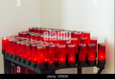 Reihen von roten Votiv-Kerzen in der katholischen Kirche Stockfoto