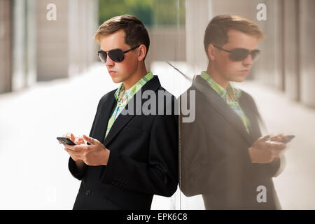 Junger Mann mit einem Mobiltelefon stehen an der Wand Stockfoto