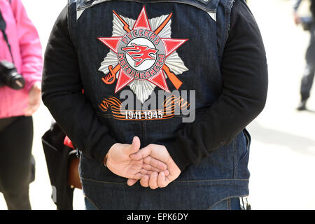 Mitglied der russischen Motorrad-Club "Nachtwoelfe" (lit.) Night Wolves) trägt eine Jacke mit Logo und Bänder, die bestehen aus schwarz und orange bicolour Muster mit dem Schriftzug "1941-1945' drauf - die Dauer des Krieges mit Hitler-Deutschland - im Deutsch-Russischen Museum in Berlin, Deutschland, 8. Mai 2015. Das Museum ist der historische Ort der deutschen Instrument der Kapitulation am 8. Mai 1945 in Berlin-Karlshorst. Die russische Gruppe begann die Tour anlässlich des 70. Jahrestages des Ende des zweiten Weltkrieges in Moskau am 25 April und kommt in Berlin am 09 Mai - wenn Russland beobachten Stockfoto