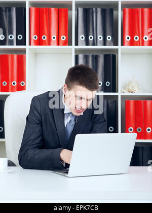 schockiert junge Unternehmer auf der Suche auf Laptop in seinem Büro Stockfoto