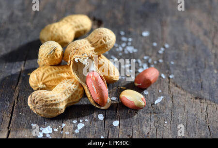 Erdnüsse in Schalen und Salz auf Holz Hintergrund Stockfoto