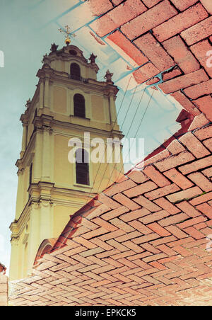 Alte Kirche in Vilnius, Litauen, im Wasser Pfütze auf Kopfsteinpflaster wider Stockfoto