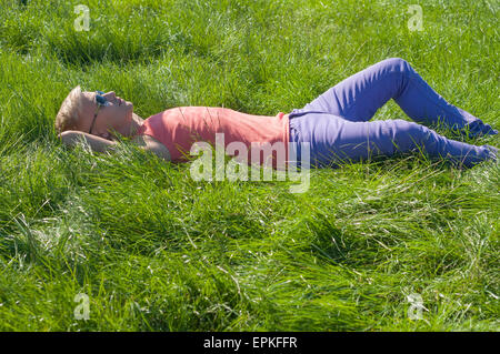 Junge trendige Mann liegt auf dem Rasen Stockfoto