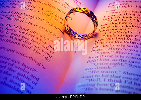 Ring mit herzförmigen Schatten auf ein offenes Buch liegend