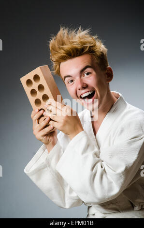 Lustige Karate-Kämpfer mit Lehmziegel Stockfoto