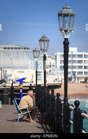 Mann sitzt auf Worthing Pier Angeln Stockfoto