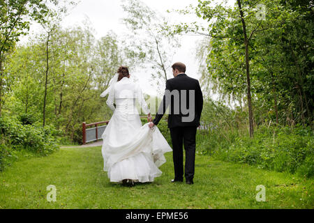 eine Braut im weißen Hochzeitskleid zu Fuß mit ihrem Bräutigam in der Natur Stockfoto