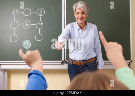 Lehrer an der Tafel mit Rechenaufgabe lächelnd Stockfoto