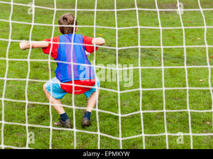 Ein kleiner Junge spielt im Tor für seine Fußball-Nationalmannschaft Stockfoto