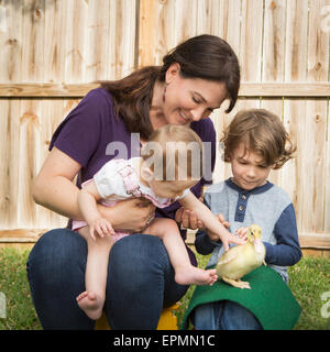 Eine Frau und zwei Kindern, mit einem jungen Entlein. Stockfoto