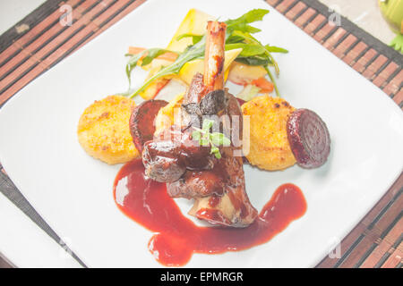 Ein Teller voller Lammkeule, Rotweinsauce, Polenta, rote Beete und Salat Stockfoto