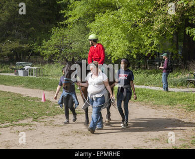 Behinderte Kinder erhalten Entwicklungs-Therapie, bekannt als Hippotherapie Reiten lernen. Prospect Park in Brooklyn, NY Stockfoto