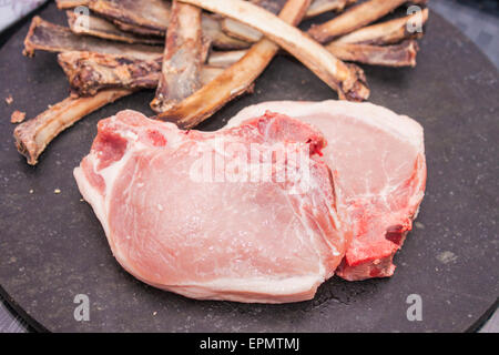 Rohe Schweineschnitzel vor ein Haufen Knochen Stockfoto