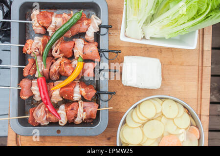 Fleischspieße, Speck und Schweinefleisch, in der Nähe von Römersalat, Chili, Halloumi und Süßkartoffeln gemacht Stockfoto