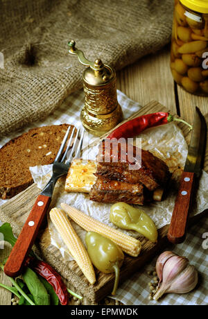 Spare Ribs mit Kräutern und Gewürzen gebacken. Hölzerne Hintergrund. Rustikalen Stil. Stockfoto