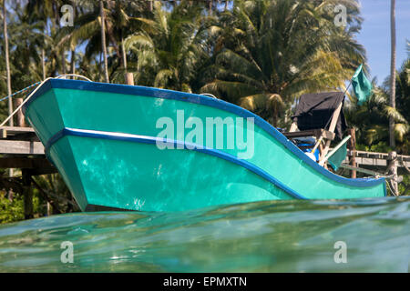 Motorboot gefesselt an einem hölzernen Pier an der tropischen Küste Stockfoto