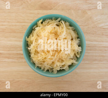 Draufsicht auf eine kleine Schüssel voller Dosen Sauerkraut auf einer hölzernen Tischplatte. Stockfoto