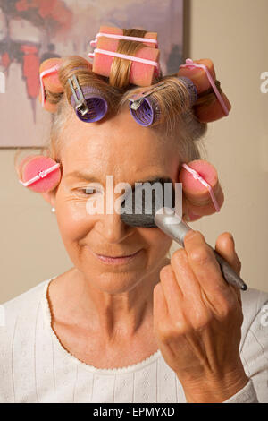 Frau in Lockenwickler beim Schminken Stockfoto