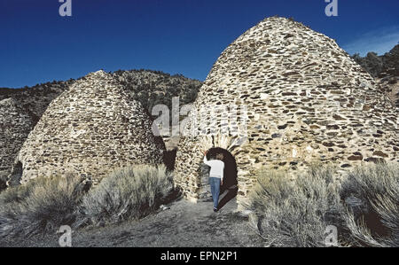 Ein Tourist inspiziert, eines der historischen Bienenstock-förmigen Kohlen-Öfen gebaut im Jahre 1877 zu Kohle für Erz schmelzen verwendet in Silber und Blei-Bergbau in der Nähe von Death Valley, Kalifornien, USA. Stein und Mörtel Strukturen wurden Wildrose Canyon in den Panamint Mountains in der Nähe von Holz gebaut, die Kiefern und Wacholder-Bäume, die langsam verbrannt wurden, für eine Woche enthalten, um die Kohle zu erstellen. Die 10 Öfen wurden aufgegeben, als die Minen stillgelegt aber ein Jahrhundert später restauriert wurden und eine Attraktion im Death Valley National Park geworden. Stockfoto