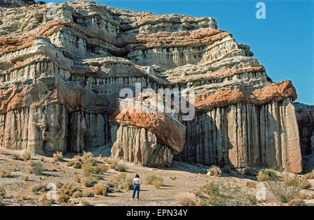 Spektakuläre Klippen und Kuppen mit Felsformationen der dramatischen Formen und leuchtenden Farben Zwerge einen Besucher am Red Rock Canyon State Park in der Mojave-Wüste am südlichsten Rand der Sierra Nevada Bergkette in Kern County, Kalifornien, USA. Die ungewöhnlichen geologischen Formen dieser natürliche Attraktion entstanden durch Wind und Regen, die weichere Gesteinsschichten unter härteren Schichten des farbigen Caprocks erodieren. Red Rock Canyon wurde der Drehort vieler Filme, Videos und Werbespots. Geführten Wanderungen und Lagerfeuer Programme werden angeboten, im Frühjahr und Herbst. Stockfoto