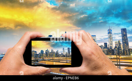 Mann und Frau hand erfassen Sonnenuntergang Skyline von Manhattan mit smartphone Stockfoto