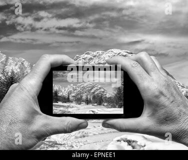 Mann und Frau Hand erfassen Alpin Winterlandschaft mit smartphone Stockfoto