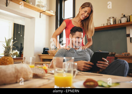 Schuss von glücklicher junger Mann und Frau mit digital-Tablette morgens. Paar mit Touchpad in Küche lächelnd. Stockfoto