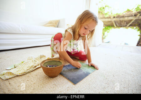 Schuss von unschuldigen kleinen kaukasischen Mädchen am Boden ein Bild mit Farbe Kreide Färbung. Schülerin zu Hause Stockfoto