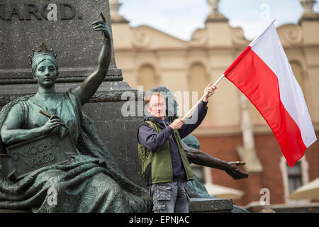 Junger Mann mit der polnischen Flagge in der Nähe von Mickiewicz-Denkmal auf dem Hauptplatz von Krakau, Polen. Stockfoto