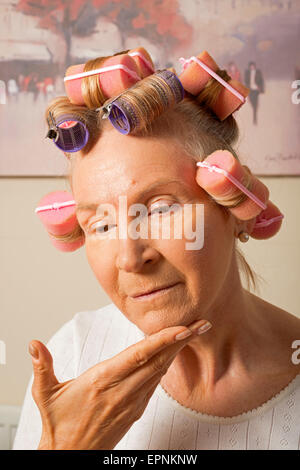 Frau in Lockenwickler beim Schminken Stockfoto