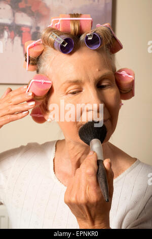 Frau in Lockenwickler beim Schminken Stockfoto