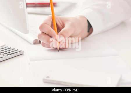 Arbeit im Büro. Geschäftsmann in Büro, schreiben mit Bleistift im Notebook. Stockfoto
