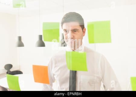 Geschäftsmann Glaswand mit Klebstoff Notizen zu betrachten. Konzeptbild von Business-Planung und Strategie. Stockfoto