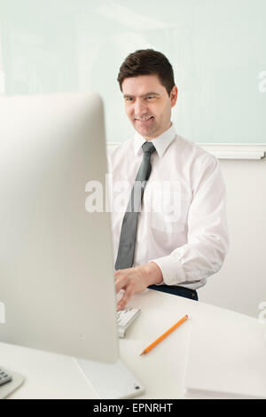 Lächelnd Geschäftsmann sitzen durch Schreibtisch, arbeiten mit Computern im Büro. Stockfoto