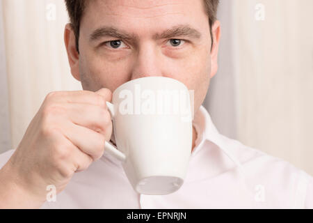 Nahaufnahme des Mannes aus Kaffeetasse zu trinken und in der Kamera suchen. Stockfoto