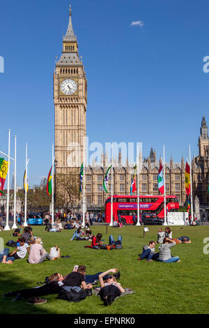 Touristen sitzen In der Sonne Bundesplatz vor den Houses of Parliament, London, England Stockfoto