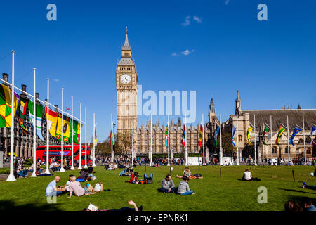 Touristen sitzen In der Sonne Bundesplatz vor den Houses of Parliament, London, England Stockfoto