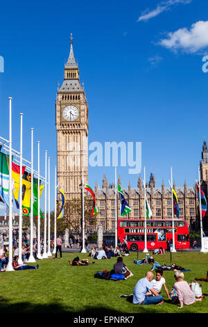 Touristen sitzen In der Sonne Bundesplatz vor den Houses of Parliament, London, England Stockfoto