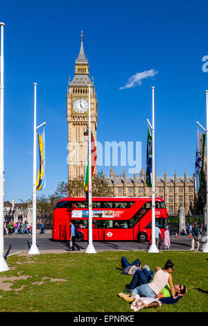 Touristen sitzen In der Sonne Bundesplatz vor den Houses of Parliament, London, England Stockfoto